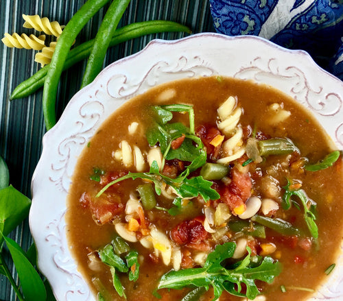 beautiful ministrone with fresh arugula in a farmstyle white bowl  and garnished