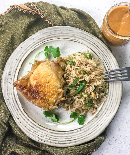 perfectly cooked chicken with rice and garnish on a country style plate and fork