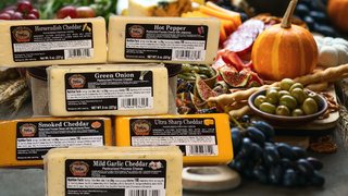 Signature Gourmet Cheeses Collection image with fresh vegetables and treats in the background